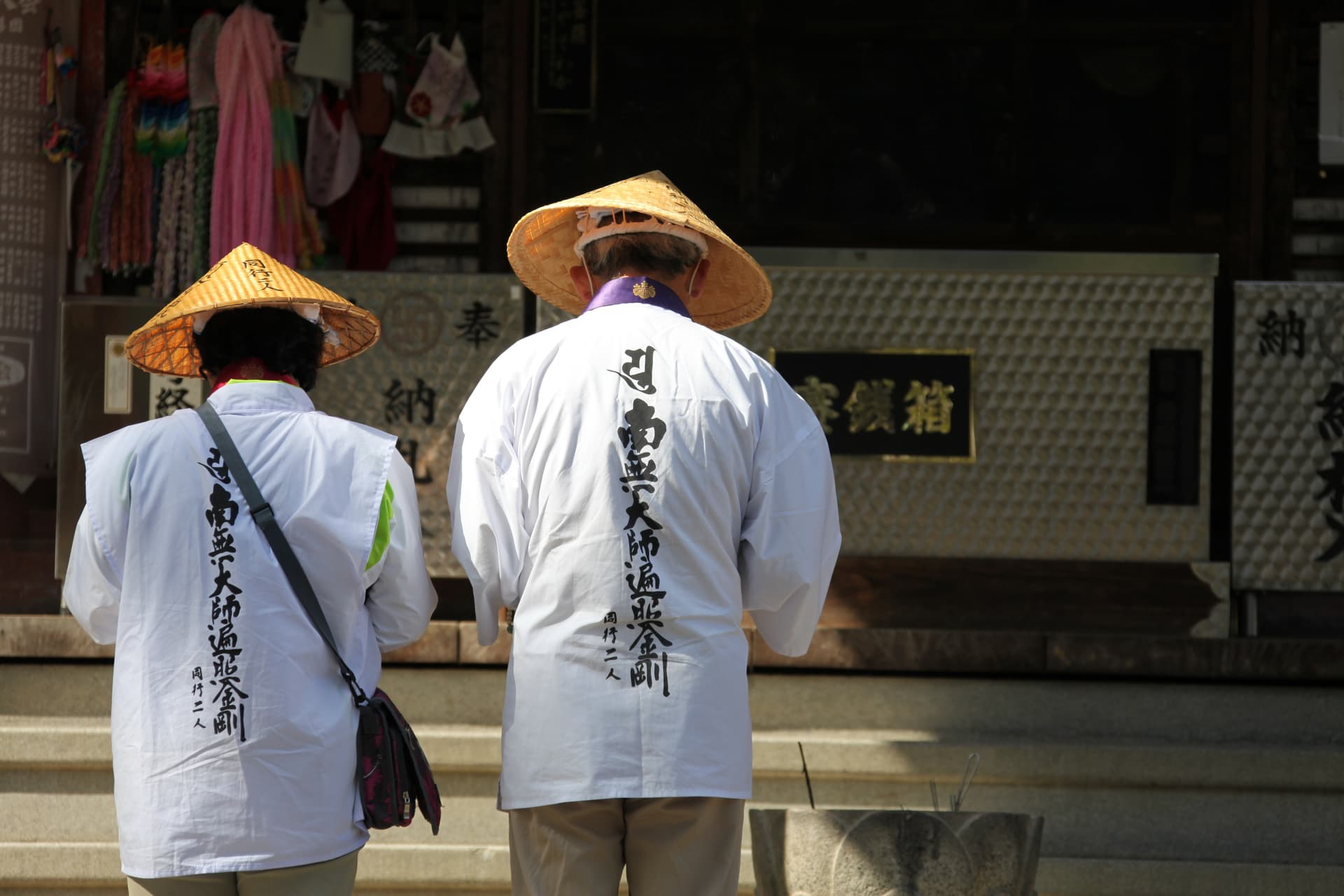白衣と菅笠を身に着けたお遍路さんの後ろ姿